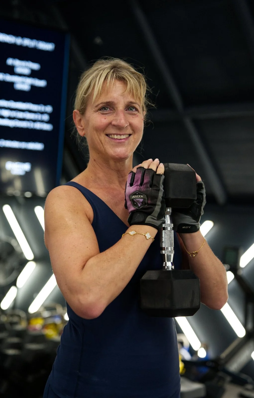 Smiling Engine Room member holding a heavy dumbbell in the training hall