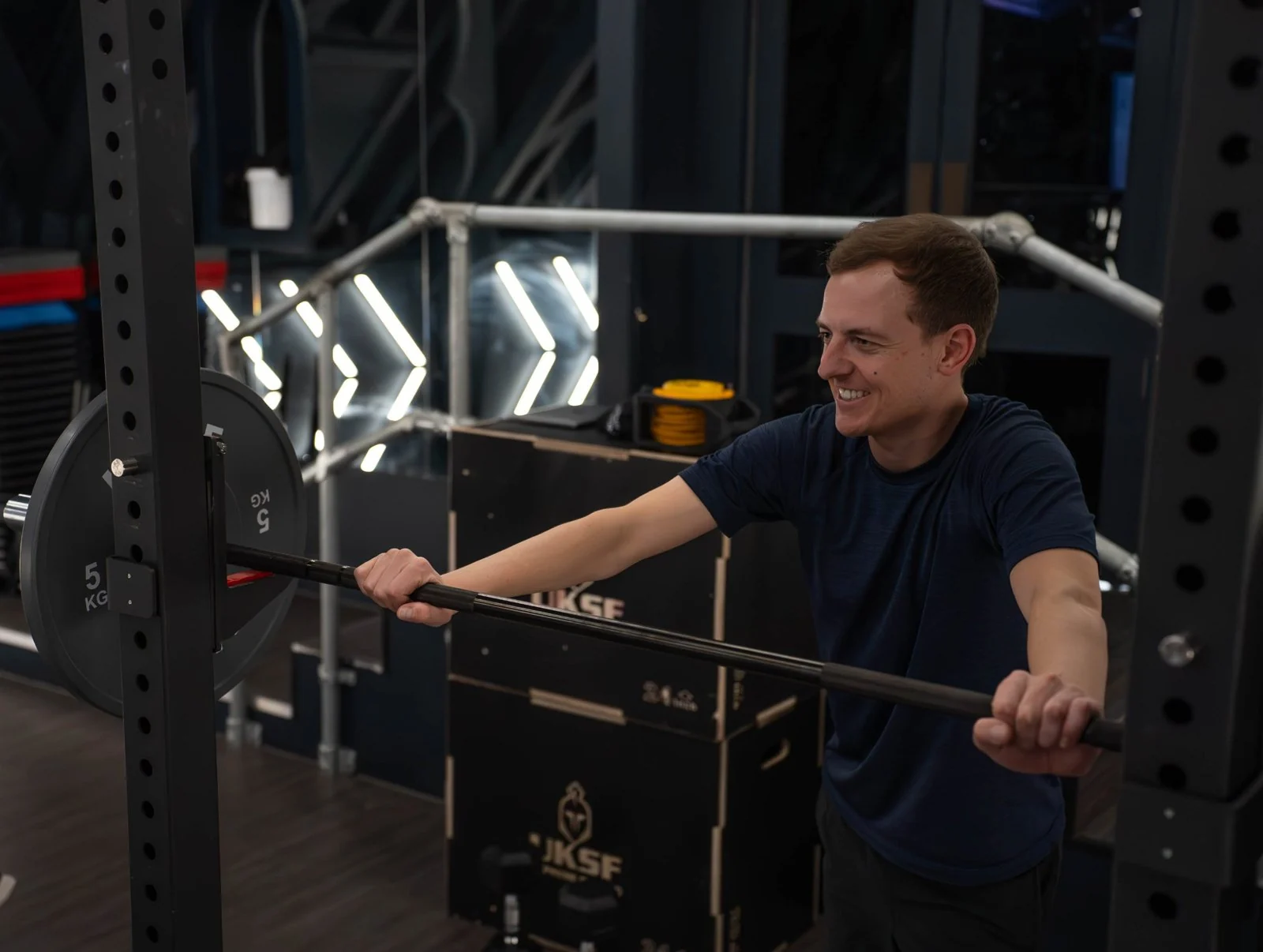 Smiling member setting up a barbell in the rack at Engine Room