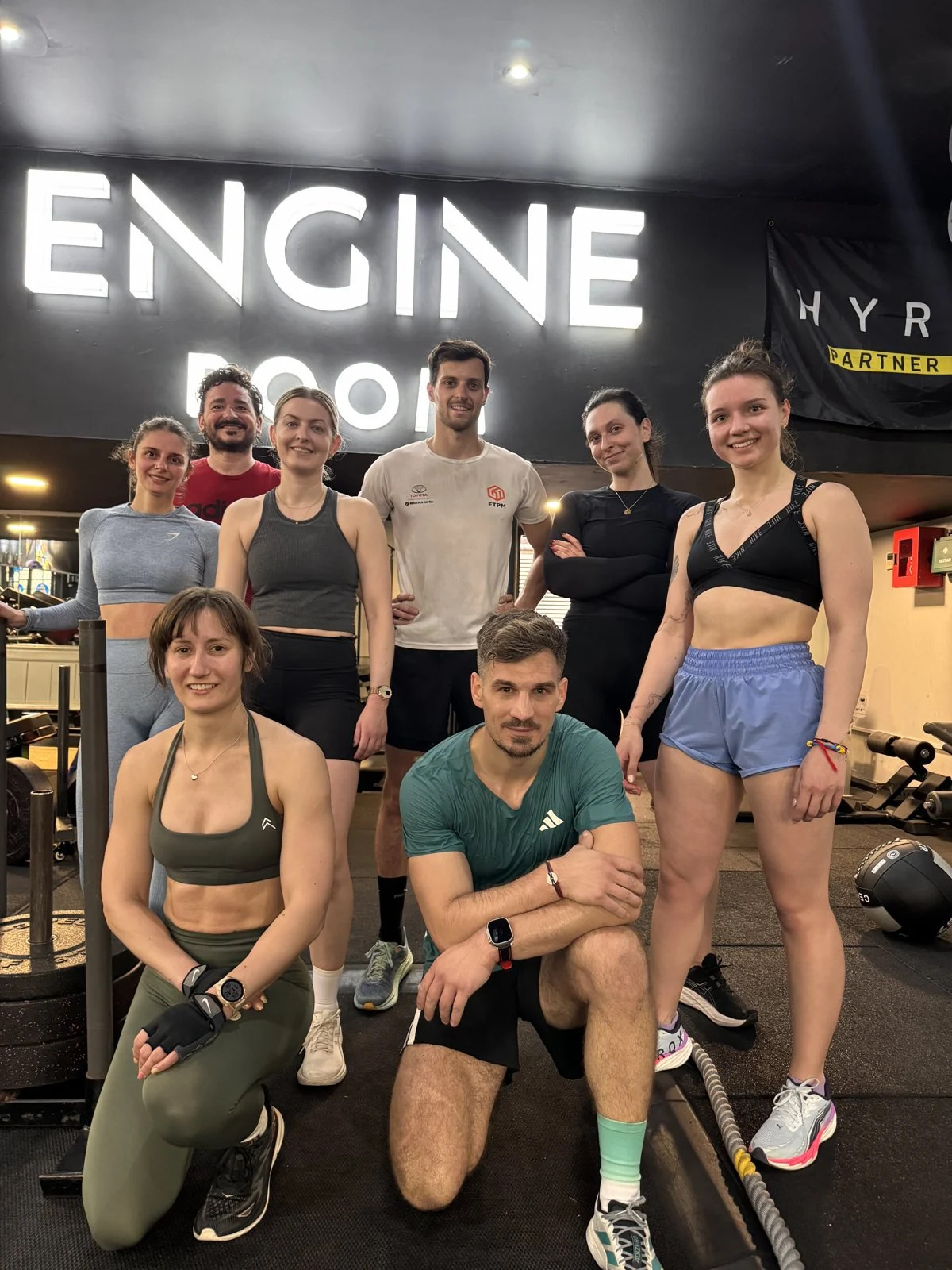 A Team Sweat group under the Engine Room sign